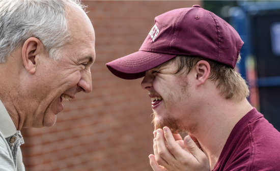 Image showing a happy moment of laughter between an old man and a smiley guy with Down Syndrome